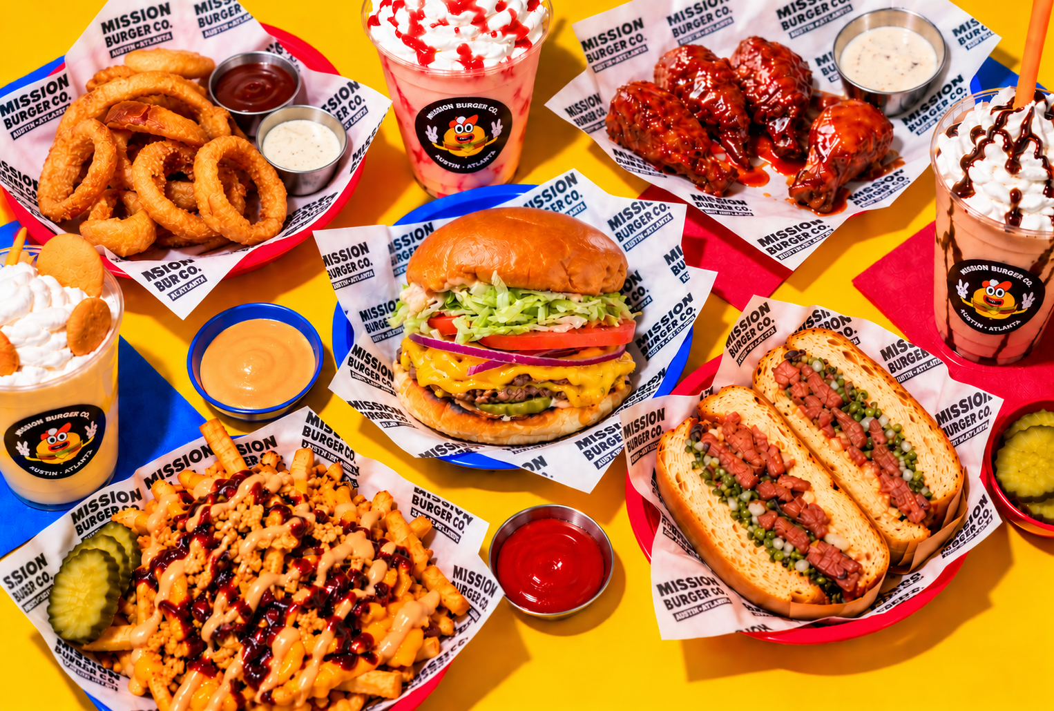 A colorful spread of Mission Burger Co. dishes — burgers, fries, wings, shakes and a sandwich